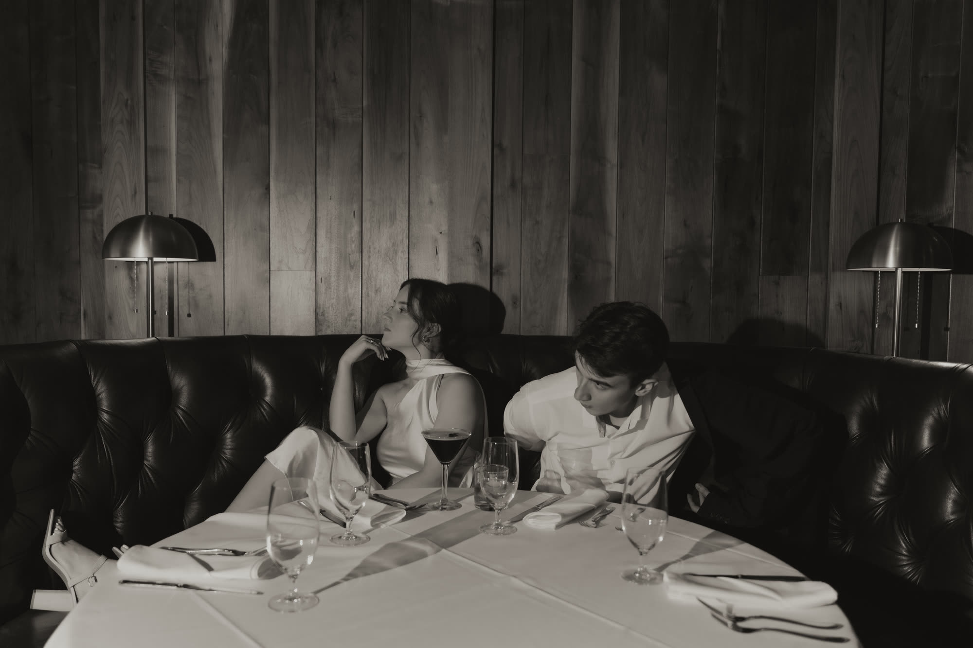 Ayden and her husband sitting in a dark leather booth at a restaurant table.